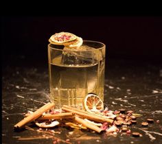 a glass filled with liquid next to some cinnamons and other things on the table