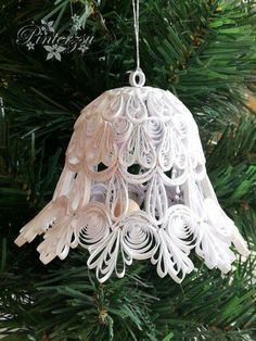 an ornament hanging from a christmas tree in the shape of a bell with feathers