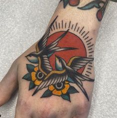 a person's hand with a bird and flower tattoo on the left side of their palm