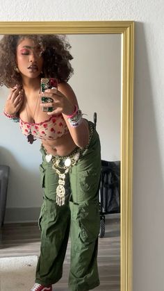 a woman taking a selfie in front of a mirror wearing green pants and red shoes