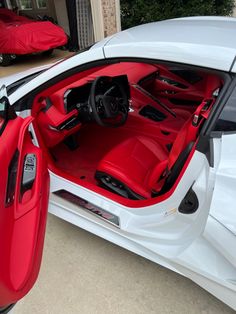 the interior of a white sports car with red leather seats and door open to show the driver's side view