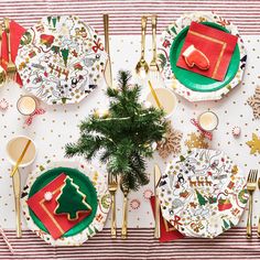 a table set for christmas dinner with plates and napkins, gold cutlery, silverware