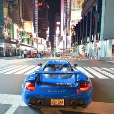 a blue sports car parked on the side of the road in front of tall buildings