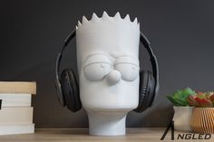 a white headphone holder sitting on top of a table next to books and a potted plant