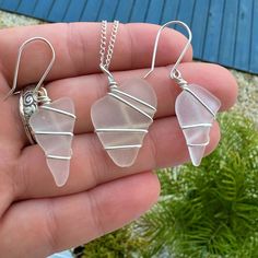 three pieces of glass sitting on top of a person's hand in front of some plants