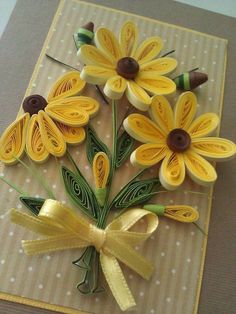 some yellow flowers are sitting on top of a brown and white card with gold ribbon