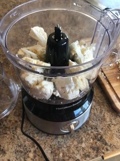 a blender filled with bananas sitting on top of a counter next to a cutting board