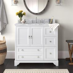 a white bathroom vanity with a round mirror above it and yellow flowers on the counter