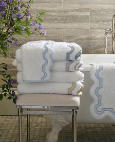 a stack of white towels sitting on top of a chair next to a bath tub