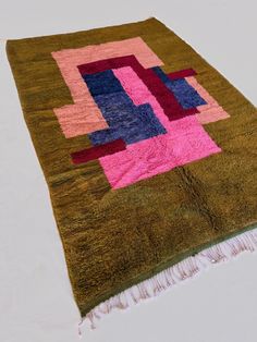 a green rug with pink, blue and purple squares on it's center piece