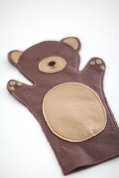 a brown teddy bear shaped oven mitt on a white surface