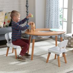 a little boy sitting at a table playing with wooden blocks and building toys in his living room