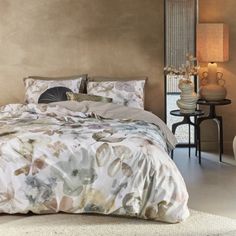 a bedroom with a large bed covered in floral comforter and pillows, along with two night stands