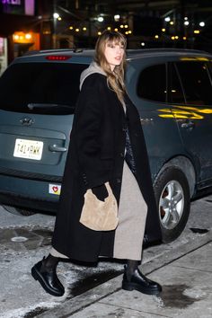 a woman is walking down the street at night with her handbag in her pocket