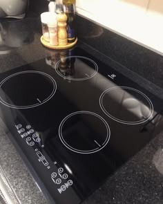 a black stove top with three burners in the middle and bottles on the counter