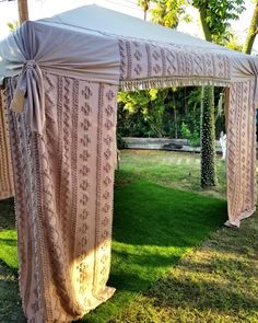 an outdoor wedding ceremony setup with draping and bows on the top, grass