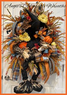 an orange and black wreath with pumpkins, leaves and other fall decorations on it