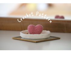 a small crocheted heart sitting on top of a wooden tray with the words crochet pattern above it