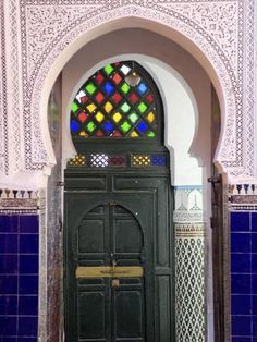 an ornate doorway with a stained glass window in the center and tiled walls surrounding it