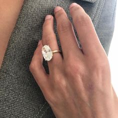 a woman's hand wearing a gold ring with a white flower on the side