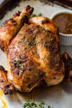 a roasted chicken on a baking sheet with dipping sauce