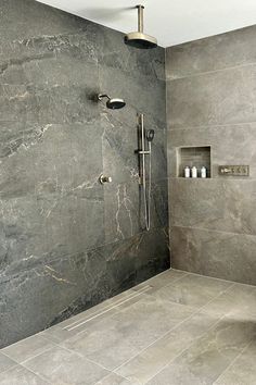 a walk in shower sitting next to a tiled wall