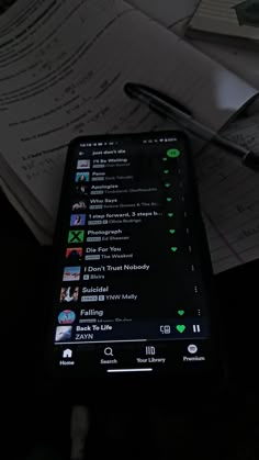 a cell phone sitting on top of a desk next to a pen and paper with notes