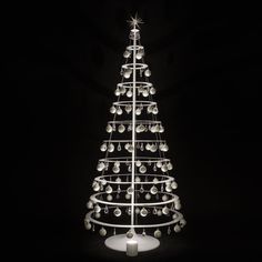 a lighted christmas tree in the dark with balls on it's base and lights