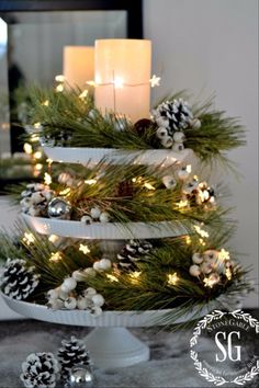 a christmas tree with pine cones and candles in it is sitting on top of a table