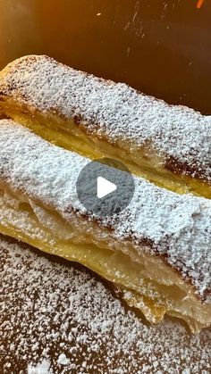 two pastries covered in powdered sugar sitting on top of a table next to each other