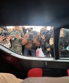 a group of people taking pictures in a car mirror