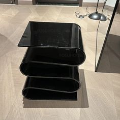 a black glass table sitting on top of a hard wood floor