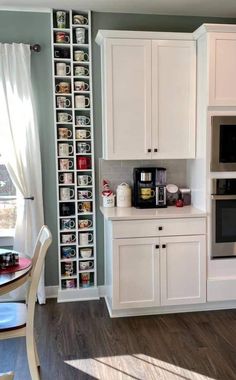 a kitchen with white cabinets and gray walls, an oven in the middle is next to a dining room table