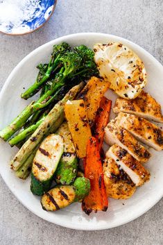 a white plate topped with chicken, vegetables and broccoli