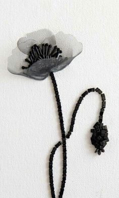 a black beaded necklace with a white flower on it and a string attached to it