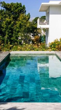 an empty swimming pool in front of a white house