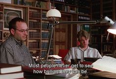 two men sitting at a desk in front of books