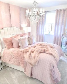 a bedroom with pink and white bedding, chandelier and window in the background