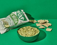 a bag of chips next to a bowl of guacamole and crackers