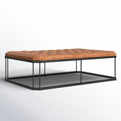 a brown leather bench sitting on top of a black metal frame table with an ottoman underneath it