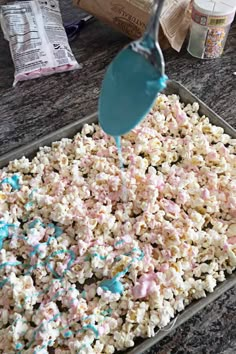 sprinkles are being poured onto a tray of popcorn that is on the counter