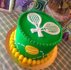 a green cake with tennis rackets on it sitting on a checkered tablecloth