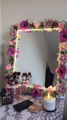 a table with a mirror, candle and various makeup items on it in front of the mirror