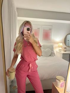 a woman taking a selfie in front of a mirror while wearing pink overalls