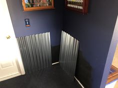 the corner of a room with blue walls and metal radiators on the wall