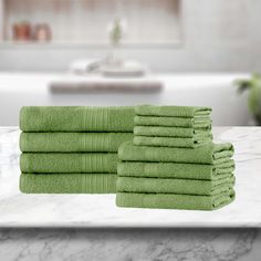 six green towels stacked on top of a white counter