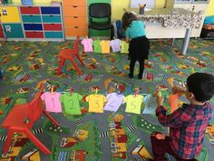 two children playing with clothes on the floor in a room full of toys and desks