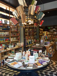 a room filled with lots of books on top of a checkerboard floor and a chandelier hanging from the ceiling