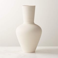 a large white vase sitting on top of a table next to a wall and floor