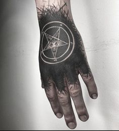 a man's hand with a pentagramil tattoo on it and black ink